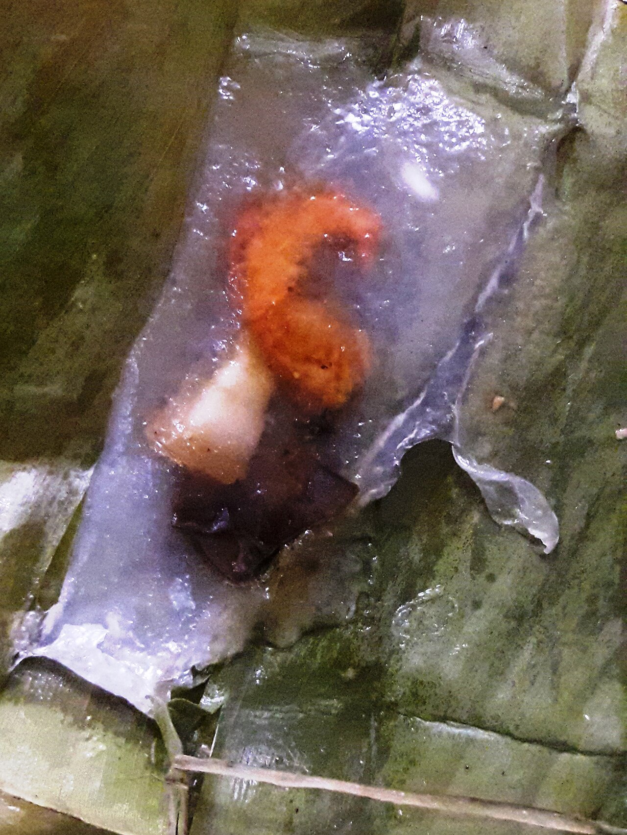 Chiếc bánh lọc lá đã mở lá với nhân tôm đỏ bên trong